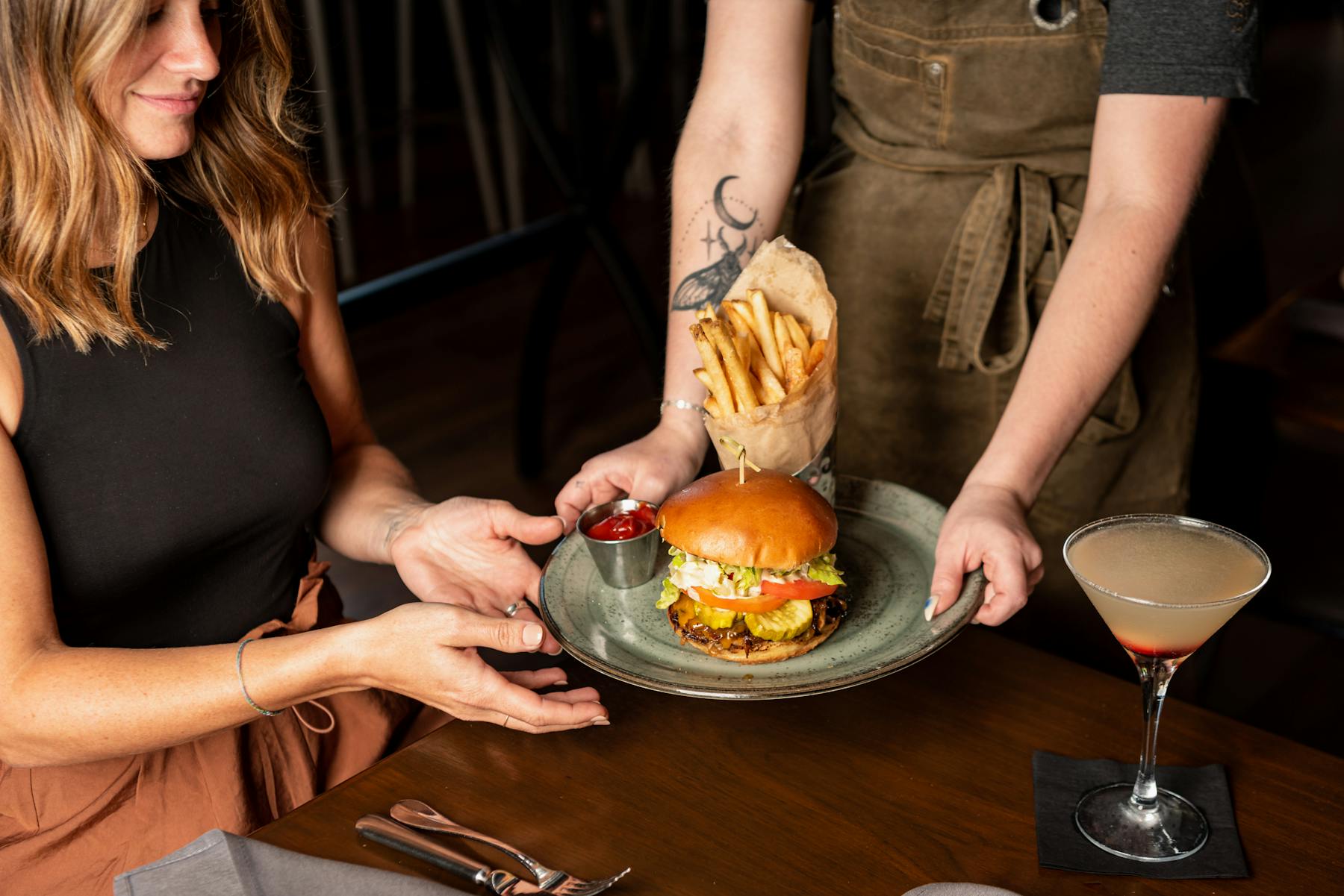 a woman sitting on a cutting board with a cake on a table